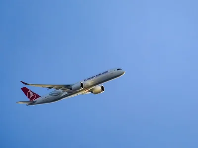 A THY airplane is flying in the blue sky. Photo by İrfan Simsar on Unsplash