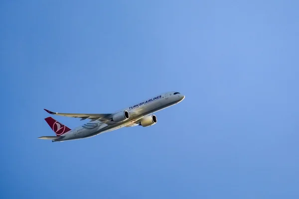 A THY airplane is flying in the blue sky. Photo by İrfan Simsar on Unsplash